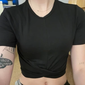 Svart croppad topp från H&M Divided - Säljer en svart croppad topp från H&M Divided. Den är kortärmad och har en tight passform, perfekt för en casual look. Toppen är i bomull och känns skön mot huden.