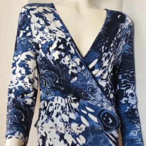 Blå och vit omlottklänning med påfågelsmönster Maxiklänning Vintageklänning Lyx Svenska kvalitetsmärket Vera Velour Nypris 1119 Toppskick Bundlerabatt Fri frakt - Säljer en elegant långklänning i blått och vitt med ett unikt påfågelsmönster. Klänningen har en omlott-design, trekvartsärmar och maxilängd, vilket ger den en elegant touch. Perfekt för både vardag och fest!  Svenska kvalitetsmärket Vera Velour. Nypris 1195 kronor. Passar dig med storlek 36 eller storlek 38.  Slutsåld. Som ny. Mått: längd 150 cm, byst 90, midja 80, höft 90. Mkt stretchig. Stl 36-38. 94 procent viskos, 6 procent elastan. 