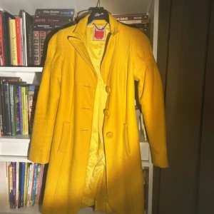 Gul kappa från Miss Sixty - Säljer en snygg gul kappa från Miss Sixty i storlek S. Den har en klassisk design med knappar framtill och långa ärmar. Perfekt för att lysa upp din garderob! 💛 