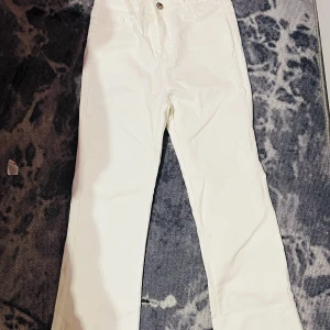 Vita skin byxor  - Snygga vita jeansbyxor med hög midja och straight passform. Perfekta för en stilren look. Byxorna har en klassisk design med knapp och dragkedja framtill.