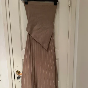 Beige klänning från ADOORE - Beige Lausanne Bandeau klänning från Adoore i storlek 38. Helt ny oanvänd med prislapp på. 