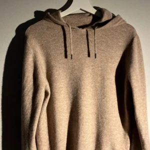 Beige hoodie i kashmir - Säljer en supermjuk beige hoodie i kashmir. Perfekt för kyliga dagar med sin mysiga huva och dragsko. En stilren och bekväm tröja som passar till det mesta. Perfekt för dig som älskar lyxigt material och enkel design.