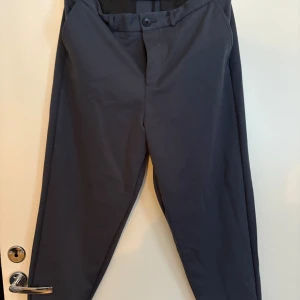 kostymbyxor - Snygga kostymbyxor med en klassisk design. Byxorna har en midwaist passform och stängs med knappar. Perfekta för en stilren look. Storlek 32/34