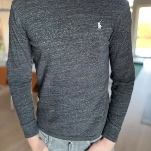 Grå långärmad tröja från Polo Ralph Lauren - Säljer en stilren grå långärmad tröja från Polo Ralph Lauren. Tröjan har en broderad logotyp på bröstet och är i en slim fit passform. Perfekt för en avslappnad men ändå snygg look🔥🔥🔥Helt fel fri och såklart äkta. Nu pris 1199kr nu endast 500kr