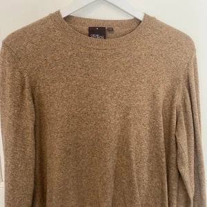 Beige tröja från Oscar Jacobson - Säljer en stilren beige tröja från Oscar Jacobson, tillverkad i Italien. Tröjan har en klassisk rund hals och långa ärmar, perfekt för en elegant och avslappnad look. Knappt använd i storlek M.