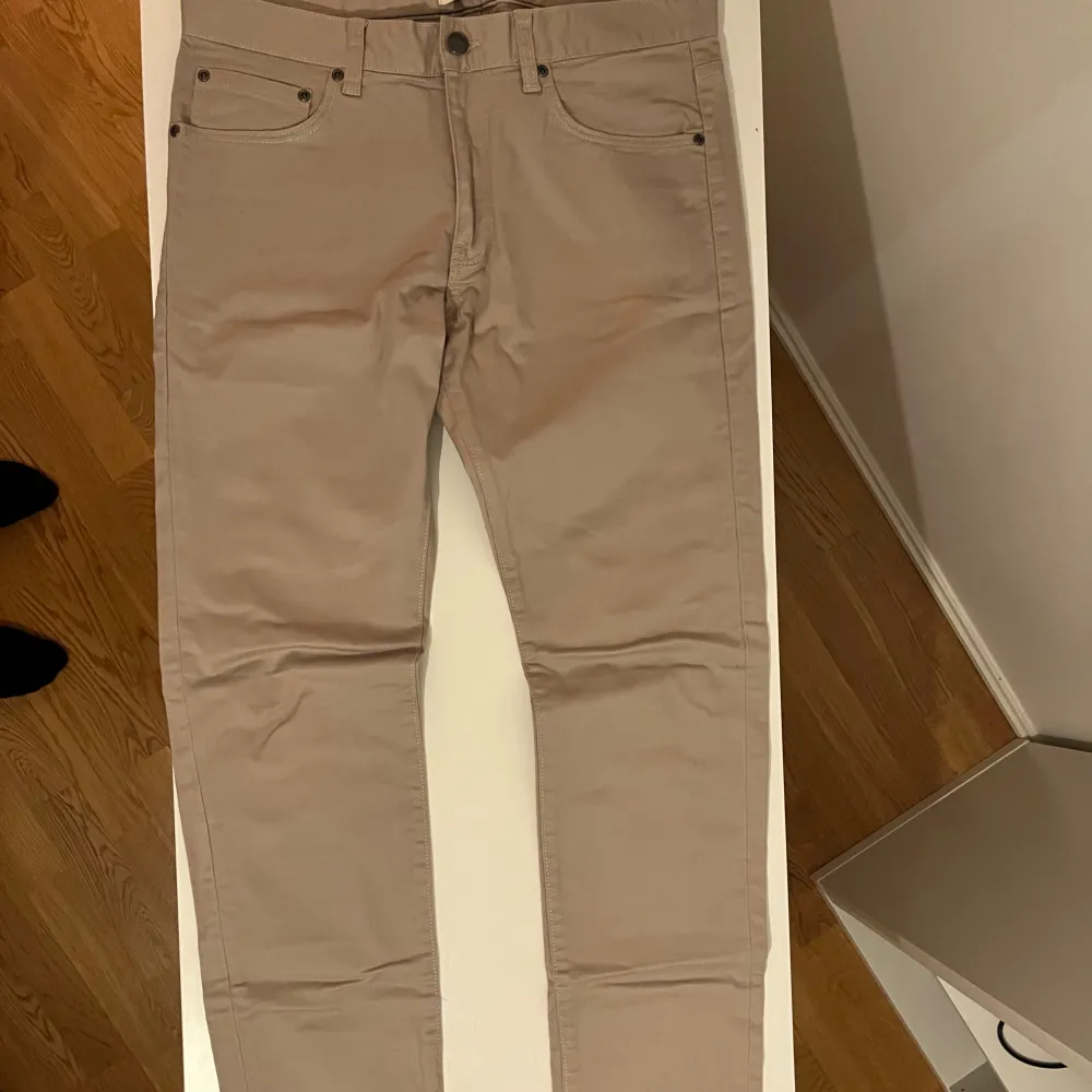 Snygga beige byxor från Dobber i storlek W32. De har en klassisk femficksdesign med knapp och dragkedja framtill. Perfekta för en stilren look.. Farkut & Housut.