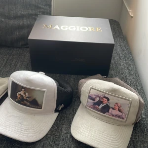 Kepsar från Maggiore - Två kepsar från Maggiore med unika fototryck på framsidan. Den ena kepsen är vit med svart mesh och den andra är grå med lite mörkare grå mesh. Perfekta för en stilren look. Orginal kartong ingår till den första kepsen pris kan diskutera också den grå kepsens kardbore är lite slö men det går även att sy ett styngn för fast storlek 🤩    