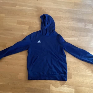 Marin blå hoodie från Adidas - Säljer denna tröja eftersom att den är för liten för mig, jag har använt denna tröja ett par gånger. Den har inga hål eller smutsiga fleckar.