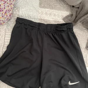 Svarta träningsshorts från Nike - Säljer ett par svarta träningsshorts från Nike. De har en elastisk midja för bekväm passform. Storlek S/M