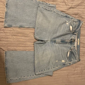Ljusblå jeans från Levi's - Säljer ett par ljusblå Levi's jeans med slitna detaljer. De har en klassisk femficksdesign och knappgylf. Perfekta för en avslappnad stil. Köpt för 1200kr!