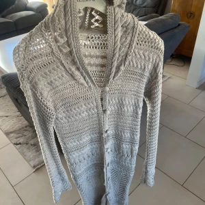 Beige stickad kofta från Odd& Molly - Säljer en snygg beige stickad kofta från Odd&Molly. Koftan har ett detaljerat stickmönster och knappar framtill. Perfekt för lager-på-lager-stil under kyligare dagar. Den har långa ärmar och en mysig huva. Använd några gånger men i bra skick. Dyr i inköp. 