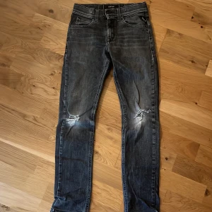 Grå replay byxor - Snygga gråa jeans från replay med slitningar på knäna. De har en klassisk femficksdesign och en dragkedja. Perfekta för en avslappnad stil.