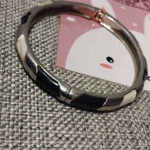 Svartvitt armband - Snyggt armband i svart och vitt med ett geometriskt mönster. Armbandet har en stilren design och är perfekt för att ge en modern touch till din outfit. Diametern är 6 cm.