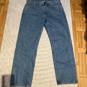 Blå jeans från Weekday - Säljer ett par blå jeans från Weekday i modellen Space Relaxed Straight. De har en klassisk femficksdesign med knappgylf och bälteshällor. Perfekta för en avslappnad stil. W30 L30