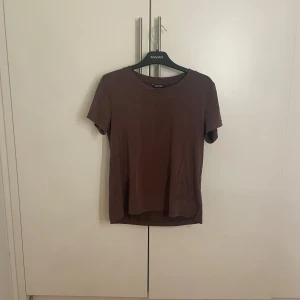 Brun t-shirt från monki  - Säljer en enkel brun t-shirt från Monki. Den har en rund halsringning och korta ärmar, perfekt för en avslappnad stil. Passar bra till jeans eller shorts för en casual look.