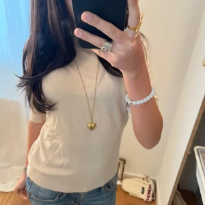 Beige kortärmad tröja - Säljer en stilren beige tröja med korta ärmar. Tröjan har en rund halsringning och är tillverkad i ett mjukt material som ger en bekväm passform. Perfekt för en avslappnad look.