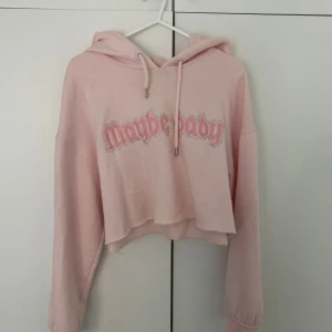 Rosa hoodie med text - Säljer en söt rosa hoodie med texten 'Maybe baby' på framsidan. Hoodien är croppad och har långa ärmar samt en klassisk huva med dragsko. Perfekt för en avslappnad stil.