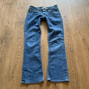 Blå bootcut jeans från Levis - Snygga blå Levis 572 bootcut jeans med klassisk femficksdesign och knappgylf. Perfekta för en avslappnad stil💘 Midjemått: 36 rakt över, Innerbenslöngden: 80