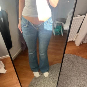 Blå bootcut jeans - Snygga blå bootcut jeans med låg midja och broderade detaljer på bakfickorna. Perfekta för en avslappnad stil. De har en klassisk femficksdesign och stängs med dragkedja och knapp. Litet hål vid bakfickan därav priset!