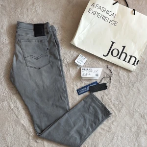 Grå Replay Hyperflex Anbass jeans - Snygga grå jeans från Replay i modellen Hyperflex Anbass. Köpta på johnells(alla tags kvar) runt 1,7k mitt pris endast 449kr. De har en modern passform och är tillverkade i ett stretchigt material för extra komfort. En liten defekt vid kylfen som man ser på bild 5 men inget som syns. Perfekta för en stilren look. Hör av dig vid funderingar och pris kan diskuteras vid snabb affär mvh Malte.202