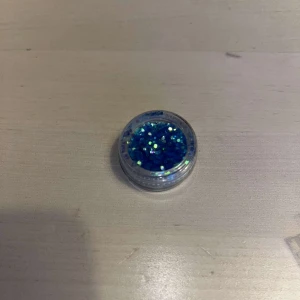 Glitter - Säljer en liten burk med blå glitter. Perfekt för att lägga till en gnistrande touch till din sminkning men även perfekt för nagel dekorationer. Kommer i en praktisk genomskinlig burk som gör det enkelt att se färgen.