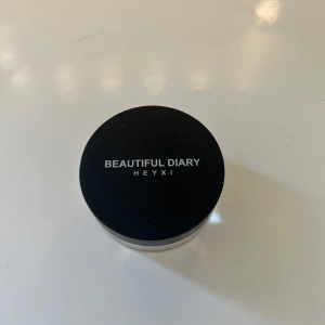 Löspuder från Heyxi - Transparent löspuder från Heyxi i en rund burk med svart lock. Perfekt för att sätta sminket och ge en matt finish. Lätt och smidig att använda för en jämn och naturlig look.