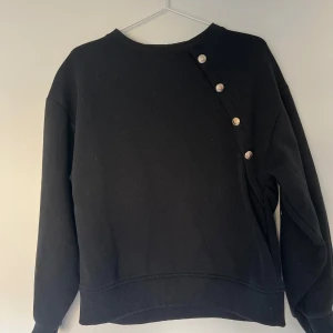 Svart tröja med knappar💗 - Snygg svart tröja med unika knappar på sidan från Zara. Tröjan har långa ärmar och en rund halsringning. Perfekt för en stilren look. Storleken på tröjan är 164, Lite åt det större hålet i storleken💗