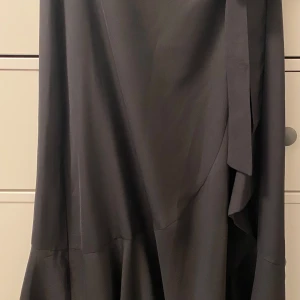 Svart omlottkjol från Gina tricot stl 34 - Svart omlottkjol med volang. Gina Tryckt stl 34, sparsamt använd.