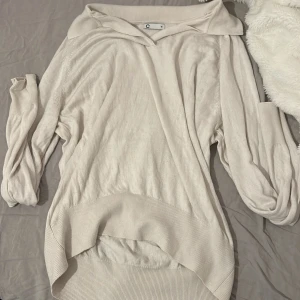 Beige långärmad tröja - Säljer en  beige långärmad tröja med en bred krage. Tröjan har en ribbad nederkant och är tillverkad i ett mjukt material.