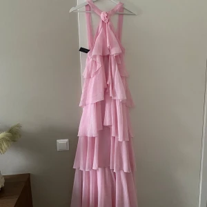 Rosa långklänning med volanger  - säljer denna populära långklänning från vero Moda! Perfekt till tex bal eller sommarens bröllop och dop! 💕 ny med lappen kvar! Storlek XS men skulle säga att den är som en S