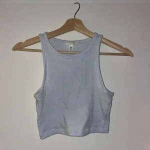 Vit ribbad linnetopp - Säljer en vit ribbad linnetopp från H&M. Toppen är ärmlös och croppad, perfekt för varma dagar. Den har en enkel och stilren design som passar till det mesta. Perfekt för sommaren!