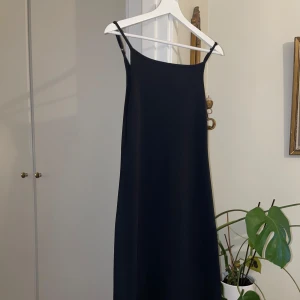 Svart långklänning från 157 - Svart långklänning från 157 med smala axelband. Klänningen har en enkel design som passar många tillfällen.