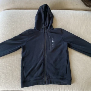 Svart hoodie från Sail Racing - Säljer en svart fullzip från Sail Racing i storlek 160. Skicket är bra, inga synliga defekter. Nypris 1000 kr, mitt pris 300. Hör av er vid frågor! 