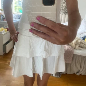 Vit volangkjol - Säljer en superfin vit volangkjol som är perfekt för sommaren! Kjolen har en elastisk midja som gör den bekväm att bära och den är gjord av ett lätt och luftigt material. Den har flera lager med volanger som ger en söt och lekfull look. 💞