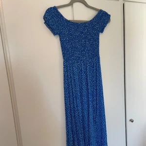 Lång blå klänning med vita prickar  - Mycket bra skick  Går att ha som off shoulder eller på axlarna.