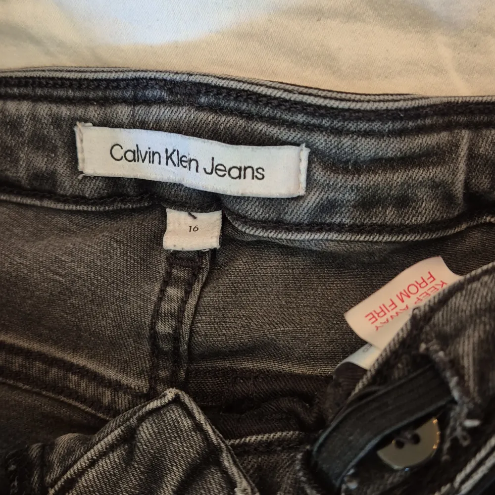 Säljer ett par snygga grå jeans från Calvin Klein. De är i storlek 16 och har en klassisk femficksdesign med dragkedja och knapp framtill. Jeansen är i bra skick och har en cool tvättad look. Perfekta för både vardag och fest!. Jeans & Byxor.