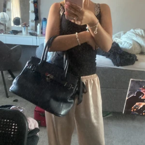 Mörkblp skinnhandväska - Säljer en snygg mörkblå handväska i skinn. Väskan har en stilren design med ett spänne framtill och två handtag. Perfekt för vardag till skola! Köptes för 350kr! Lite små defektioner inget man tänker på!