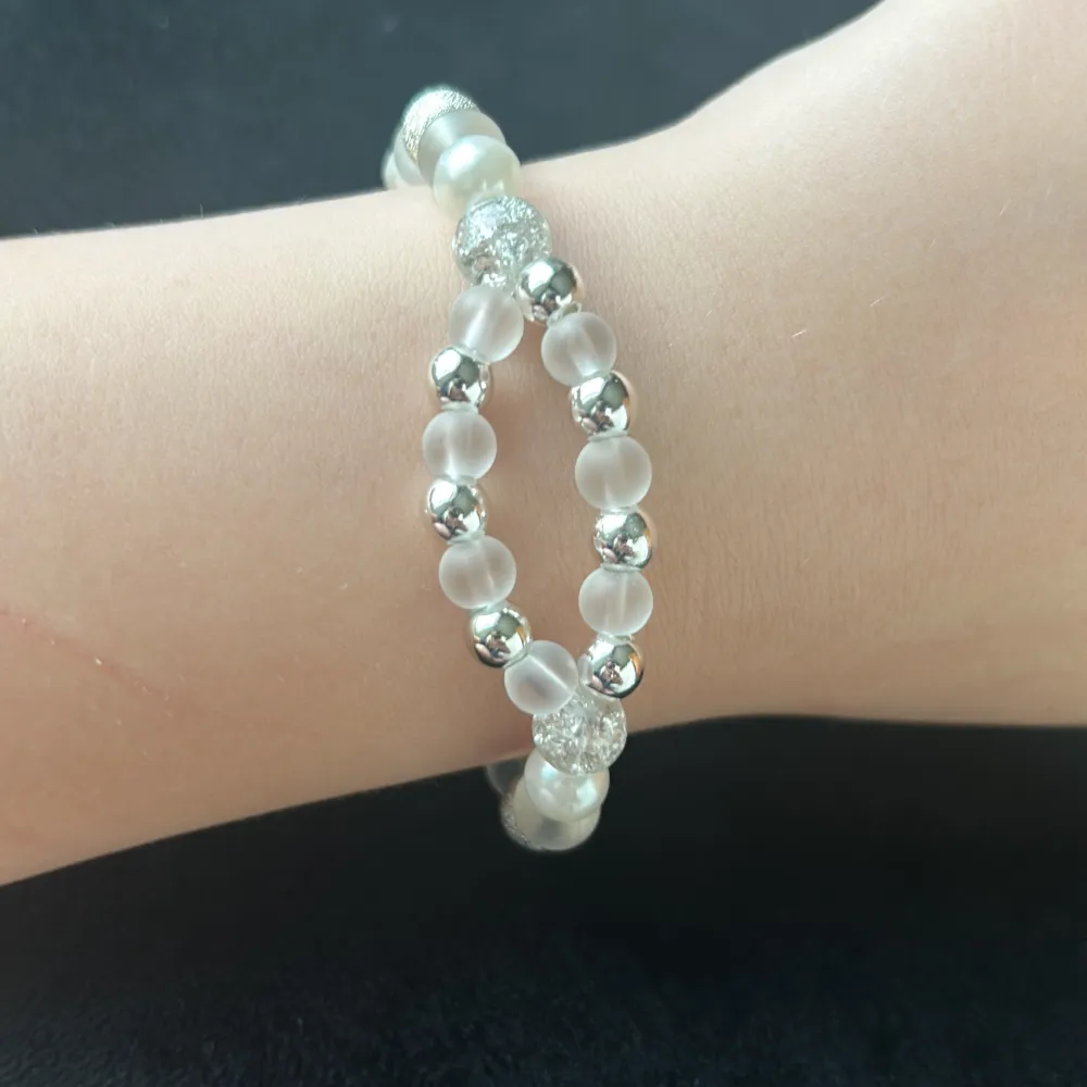 Handgjort stilrent armband, med vita och silver pärlor. Runt storlek 17 cm men kan bli större eller mindre om man vill🩷🩷🩷. Asusteet.
