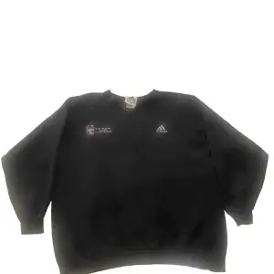 Säljer en svart sweatshirt från Adidas. Den är i storlek L och har en enkel design med Adidas-loggan på bröstet. Perfekt för höst och vinter, den är både bekväm och stilren. Tröjan har långa ärmar och är gjord av bomull och polyester. Passar bra till både vardag och träning.