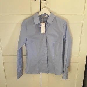 Mango figur sydd skjorta  - Hej, säljer den här populära skjortan från mango, den är ljusblå i storlek M, skulle säga att den är sann i storleken men skulle även passa S lite löst 