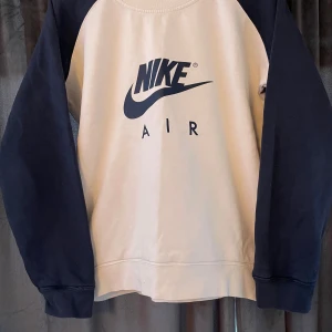 Nike Air sweatshirt i beige och svart - Säljer en snygg och bekväm Nike Air sweatshirt i vitt och mörkblå. Den är i nyskick och perfekt för både vardag och träning. Barnstorlek XL men passar som dam S-M. Den är ganska mycket använd därför de billiga priset. kontakta gärna vid frågor.