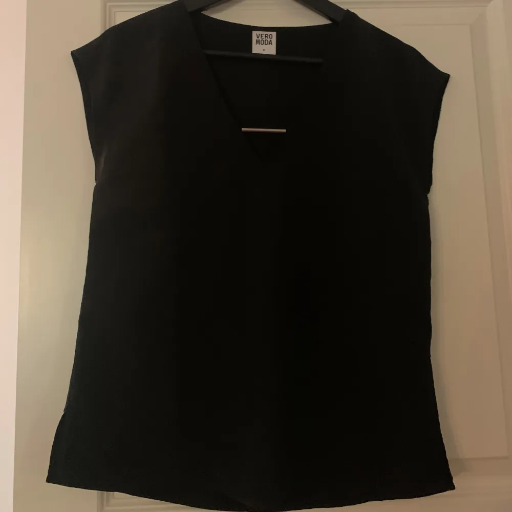 Säljer en stilren svart topp från Vero Moda. Den har en v-ringad design och är ärmlös, vilket gör den perfekt för både vardag och fest 💗. Yläosat.
