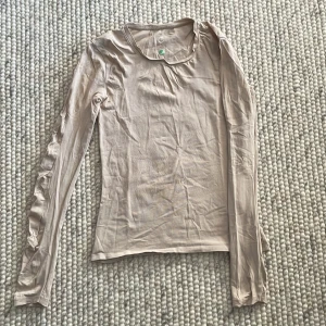 Beige långärmad topp - Säljer en stilren beige långärmad topp i ett mjukt och bekvämt material. Perfekt för både vardag och festliga tillfällen. Toppen har en enkel design som gör den lätt att matcha med olika outfits.