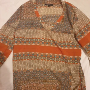 Fin blus - En vacker blus med ett mönster i orange, beige, blått och grönt. Blusen har en V-ringning och tre fjärdedelsärmar. Super fin är inte använd säljer för 50