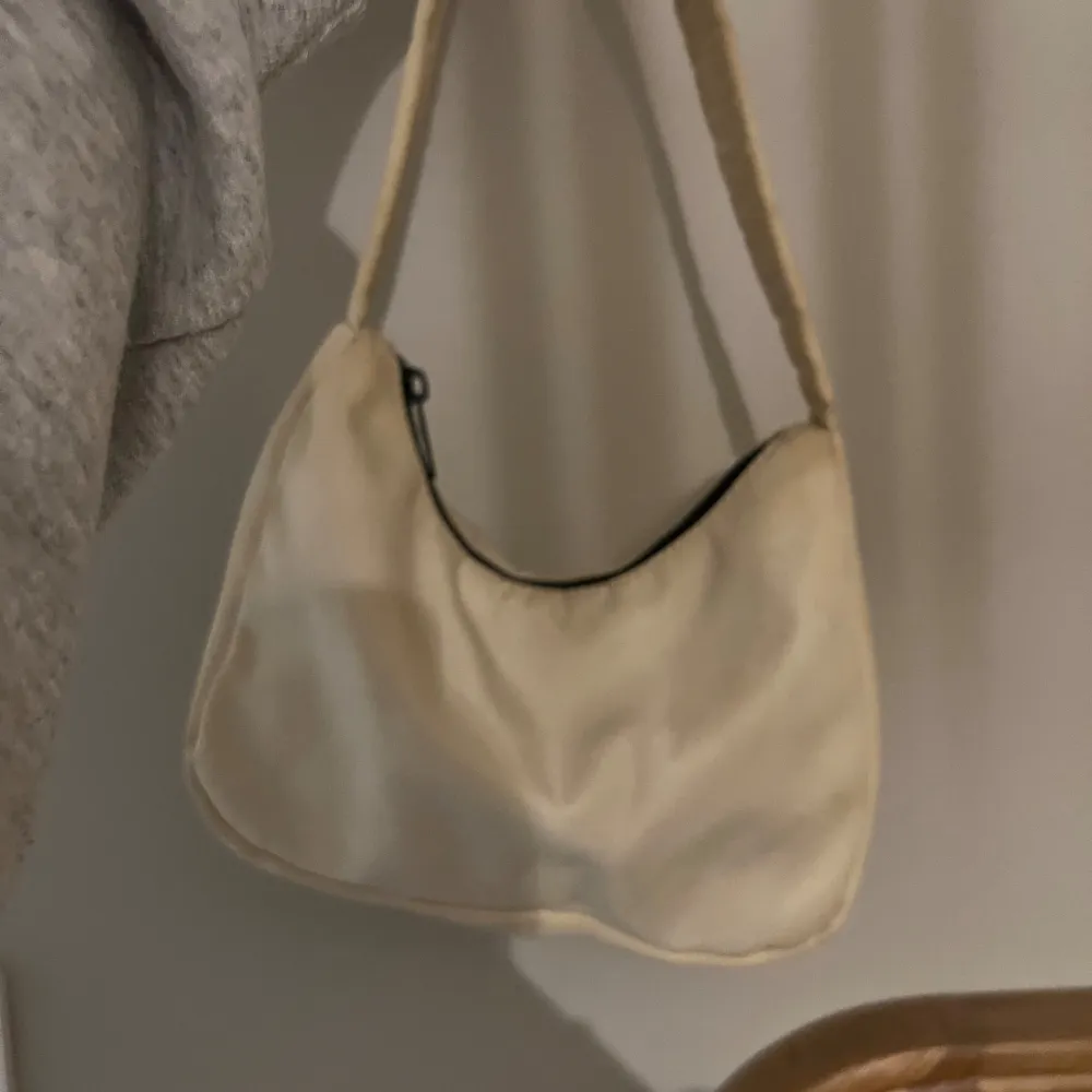 Säljer en snygg beige axelväska som är perfekt för vardagsbruk. Väskan har en praktisk dragkedja och är i en stilren design. Den är lätt att matcha med olika outfits och passar till alla säsonger.. Väskor.