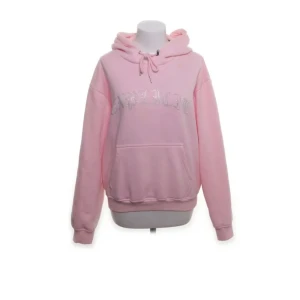 Rosa hoodie från Hidden Cult - Säljer en rosa hoodie från Hidden Cult med glittrig text på framsidan. Den har en klassisk känguruficka och justerbar huva med dragsko. Perfekt för en avslappnad stil. 💖