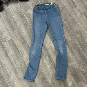 Blå jeansbyxor från Name It - Snygga blå jeansbyxor från Name It i storlek 10Y/140. De har en klassisk design med knapp och dragkedja framtill samt fickor både fram och bak. Perfekta för en avslappnad stil.