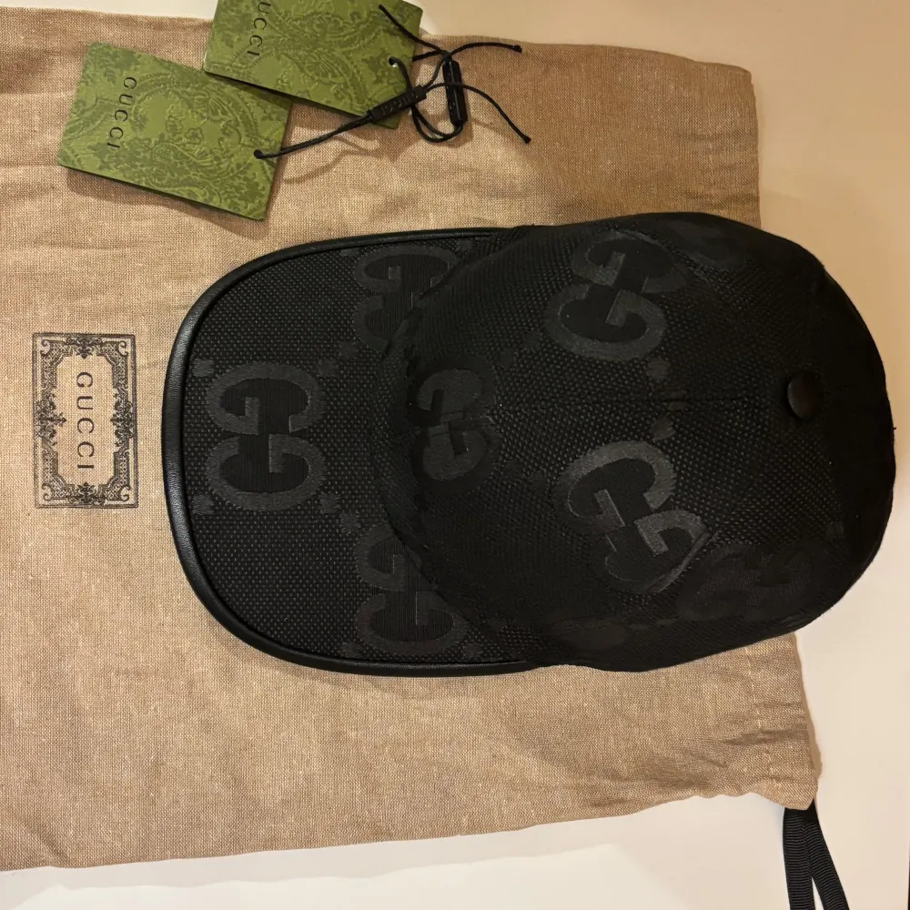 Snygg svart keps från Gucci med det ikoniska GG-mönstret. Kepsen har en justerbar rem baktill för perfekt passform. Tillverkad i ett slitstarkt material som ger en lyxig känsla. Perfekt för att ge din outfit en exklusiv touch.. Asusteet.