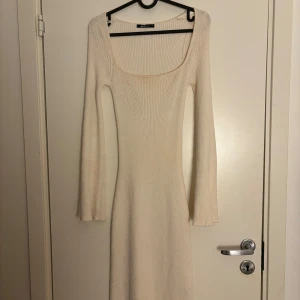 Beige ribbad klänning från Gina Tricot  - Snygg beige ribbad klänning från Gina tricot  med lång ärm och en elegant fyrkantig ringning. Perfekt för en stilren look. Klänningen har en tight passform som framhäver figuren.