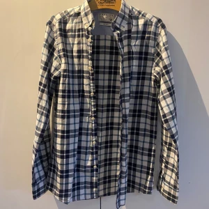 Flanell skjorta från Jack & Jones - Snygg flanell skjorta från Jack & Jones i svart och vitt. Skjortan har långa ärmar och knappar längs framsidan. Perfekt för en stilren look. Skjortan är helt ny och är därför i helt nytt skick 💫